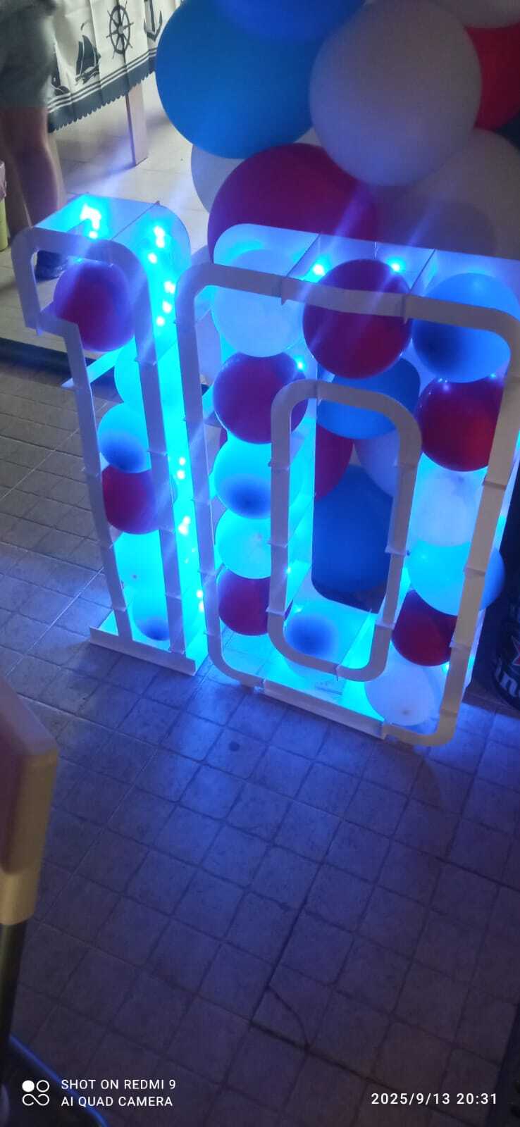 Número 10 luminoso com LEDs azuis preenchido com balões coloridos em festa de aniversário com tema naval